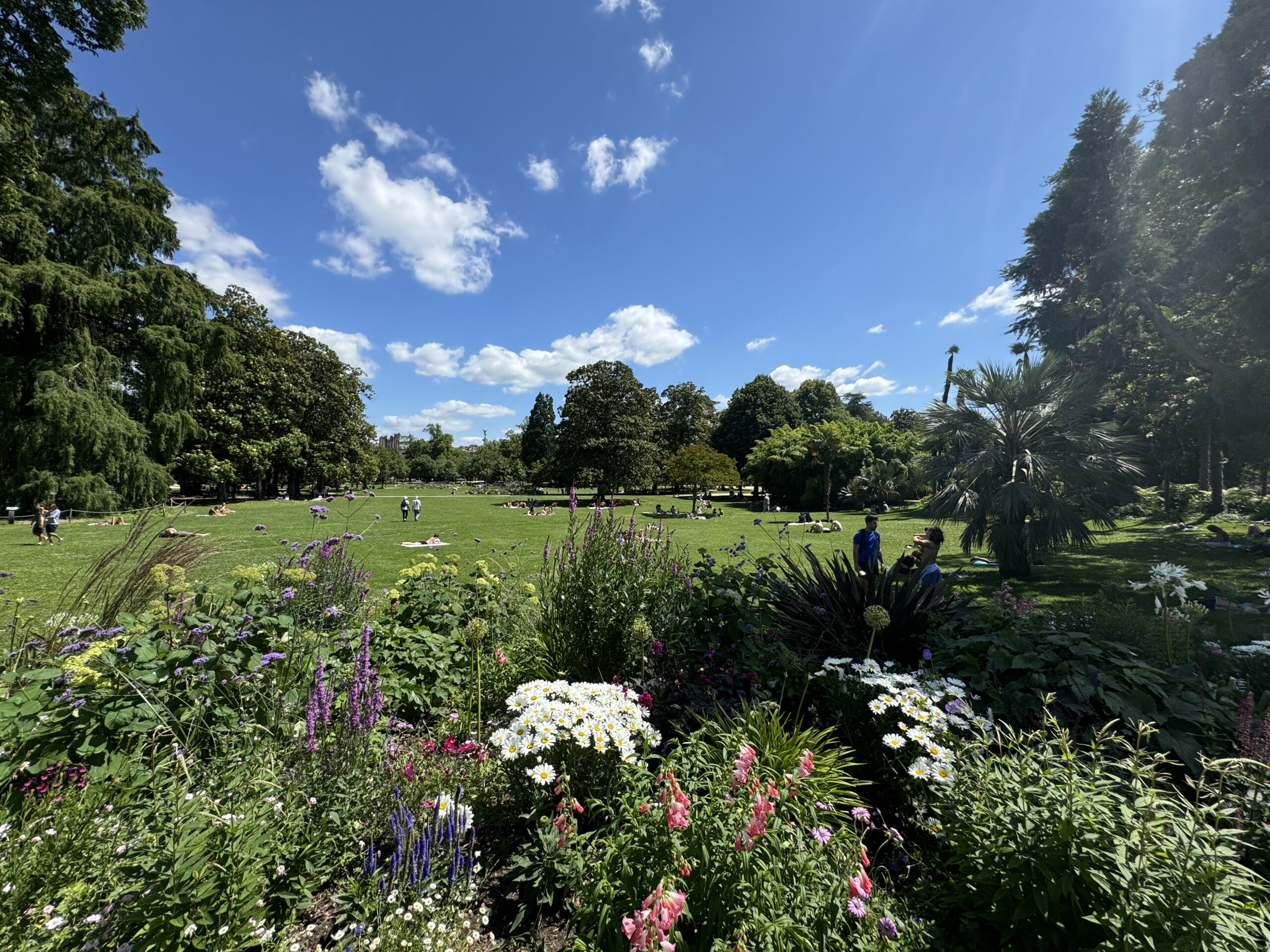 A park and flower garden in Bordeaux France with people playing in a field.